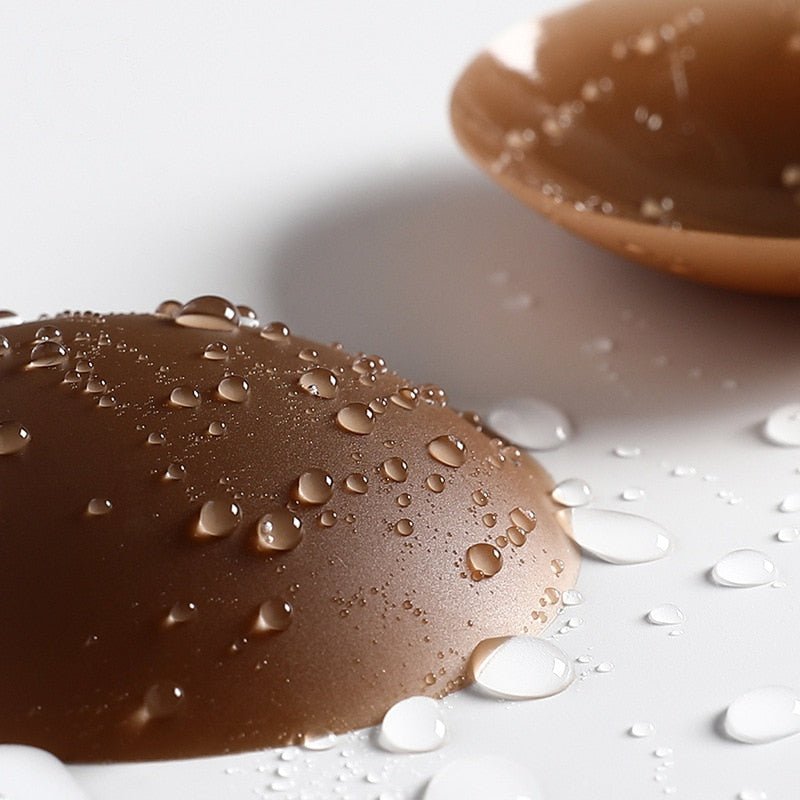 Coffee-brown reusable silicone nipple covers with water droplets, featured in a blog about cleaning silicone covers.