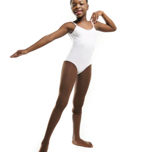 A photo of a happy young Black girl with dark skin posing in a white leotard and Blendz dark brown convertible dance tights in the color “confident cocoa” showing the tights over one foot and up her leg.